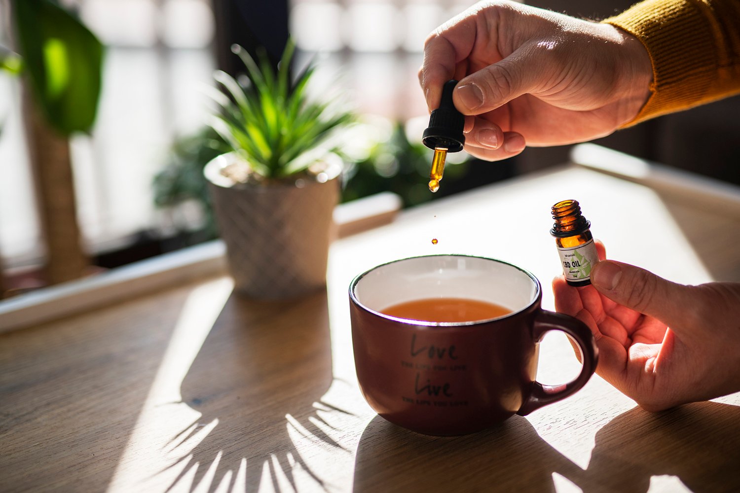 Unrecognizable man using CBD oil in his tea.