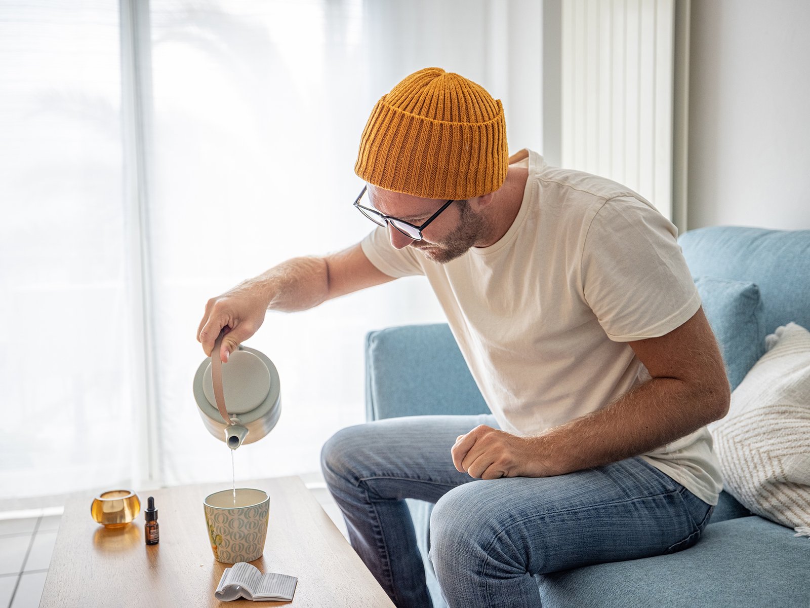 Young man using CBD for anti-inflammatory relief at home, he uses some CBD oil in a tea.