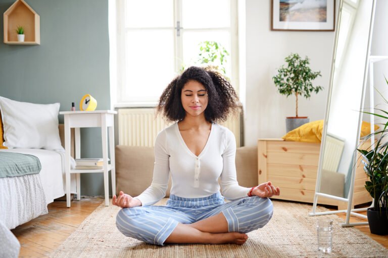 Portrait of a relaxed young woman indoors at home, doing yoga exercise.