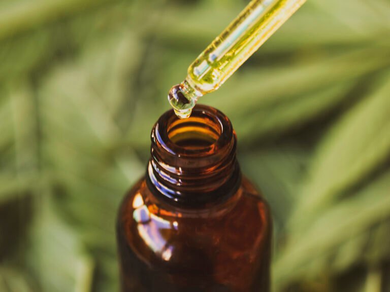 Drop of hemp based pharmaceutical CBD oil with blur background of cannbis marijuana leaves